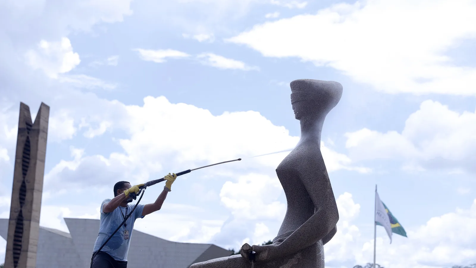 Funcionário lava a estátua A Justiça, em frente ao STF
