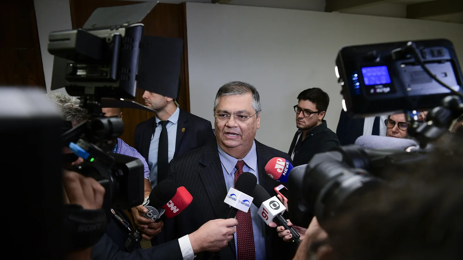 Flávio Dino cercado de microfones de jornalistas em 2023