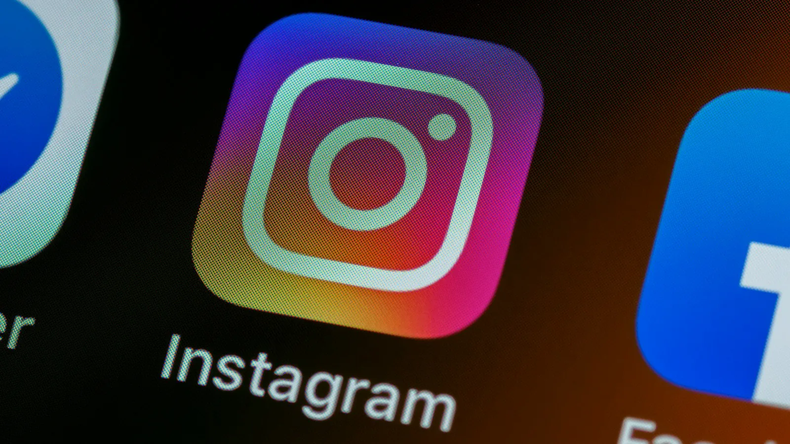 Ícone do Instagram em close na tela de um celular, entre os ícones de outros aplicativos