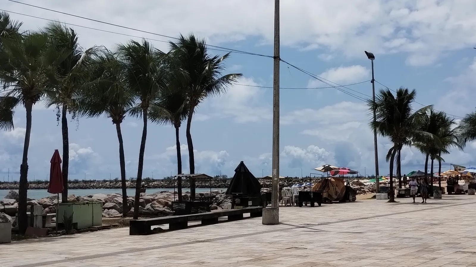 Calçadão da Praia de Iracema, em Fortaleza, com barracas e coqueiros